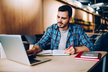 Male student browse information for studying language via online courses on netbook in coworking...