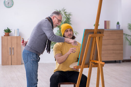 Young man taking lesson from old painter