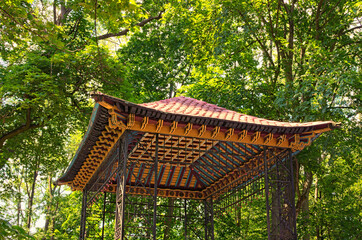Close-up view of the wooden roof of Chinese Bridge in park against blurred green leaves....