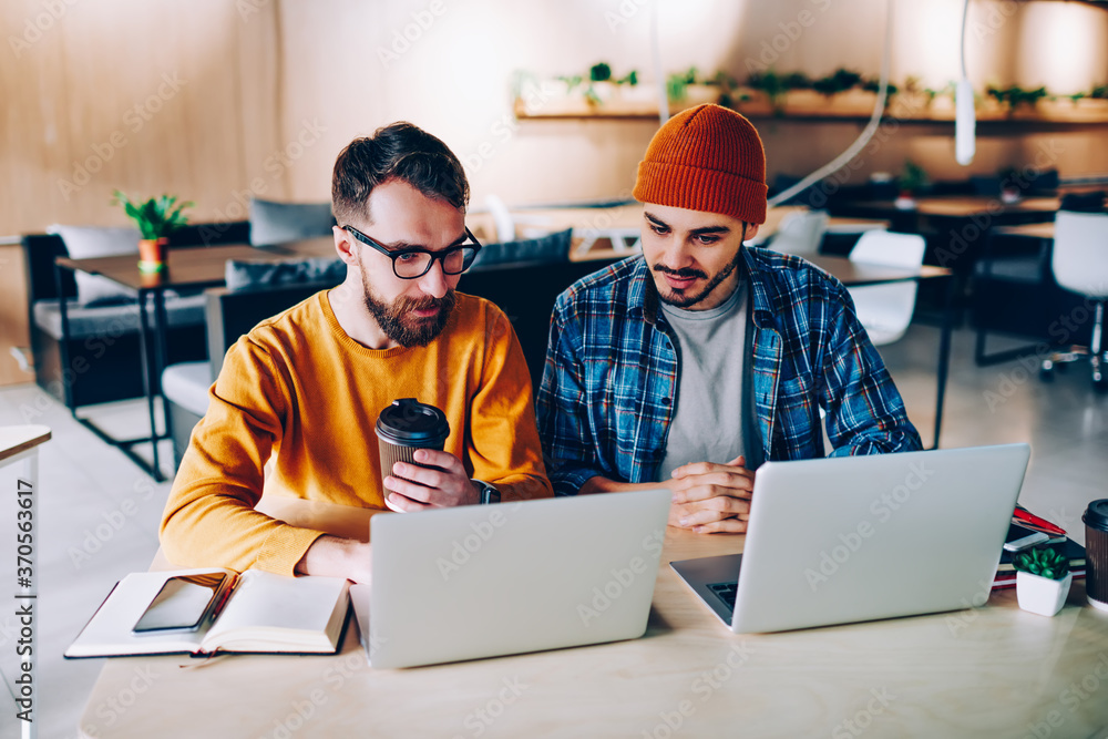 Aufkleber caucasian hipster guys working online on modern laptop devices watching webinar online for learning 