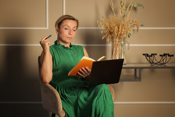 a woman in a green dress works on a laptop at home