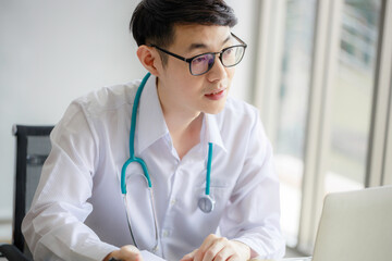 Young Asian male doctor is recording a medical history on the clipboard and explaining something to the female patient. Medical and health care concepts