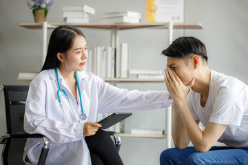 Asian female psychiatrist puts his hand on the shoulder of a young man to give encouragement as she is worried by the spread of covid 19. Disease symptoms talk about health care concept