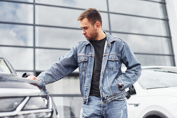 Fashionable man standing near car outdoors against modern business building