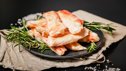 King crab leg meat on a dark plate with spices and herbs. Delicious and healthy traditional seafood. Food banner format