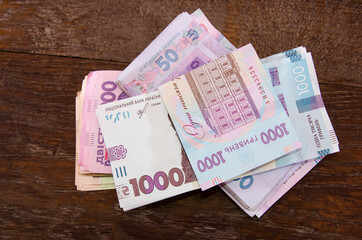 stack with hryvnia on a wooden background. 1000, 50, 200 Ukrainian hryvnias.