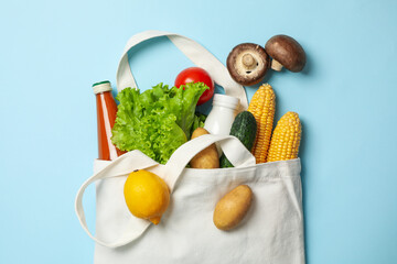Cotton bag with different food on blue background, top view