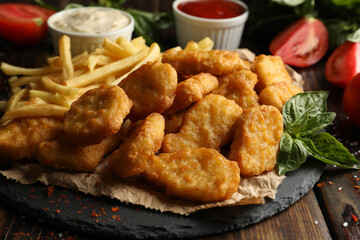 Composition with chicken nuggets, sauces and potato on wooden background