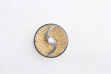 Pine nut kernels in blender jar. White background.