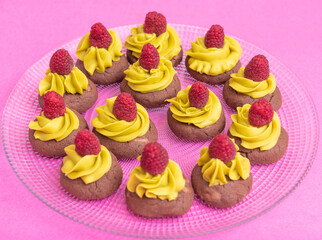 brown cookies with yellow cream and raspberries