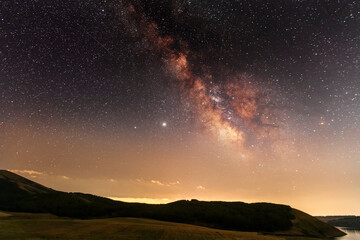 Beautiful night landscape, starry sky with bright milky way galaxy above the mountains with green...