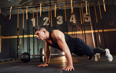 Fototapeta premium Strong man in sportive clothes doing push-ups in the gym