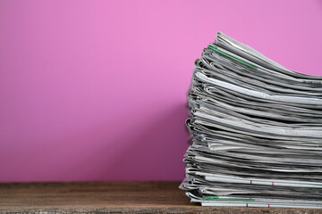 close up newspapers folded and stacked on the table with pink background