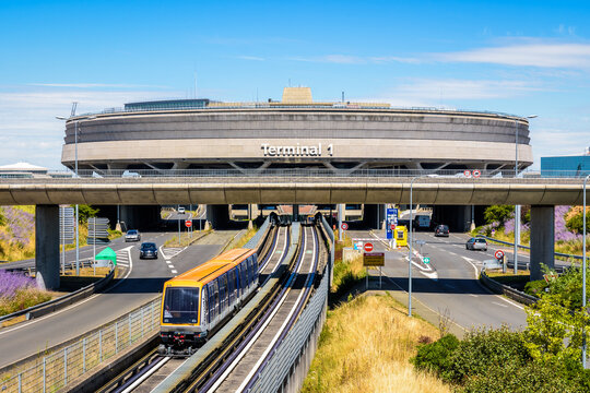 Roissy-en-France, France - July 27, 2020: A CDGVAL airport shuttle is leaving the Terminal 1 circular concrete building of Paris-Charles de Gaulle Airport on a sunny day.