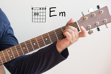 Learn Guitar - Man in a dark blue shirt playing guitar chords displayed on whiteboard, Chord E minor