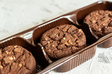 pack of american chocolate cookies with nuts on white wooden background. Fresh pastry.