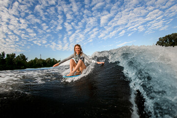 blond woman riding the waves while sitting on wakesurf board