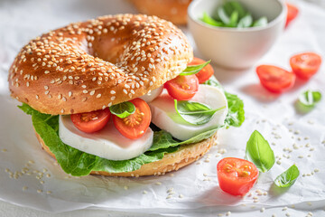 Delicious bagel with cheese, tomatoes and basil for tasty breakfast