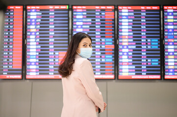 A business woman is wearing protective mask in International airport, travel under Covid-19...