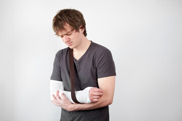 Conservative treatment of a broken arm. Attractive young upset unhappy caucasian man with plaster...