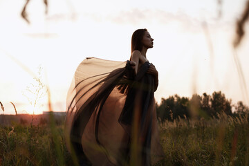 Girl at sunset in transparent fabric
