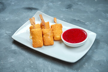Deep-fried camembert cheese with cranberry sauce in a white plate on a gray background. appetizer