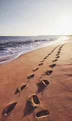 Fototapeta na wymiar Footprints on a tropical beach at sunset, color toned picture, Sri Lanka.
