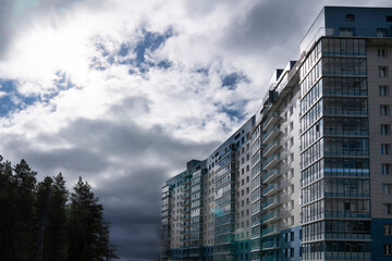residential building with balconies against the dark sky, on the edge of the forest. Modern...