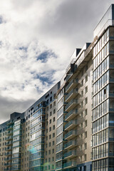 residential building with balconies against the dark sky, on the edge of the forest. Modern eco-friendly area for housing vertical photo.