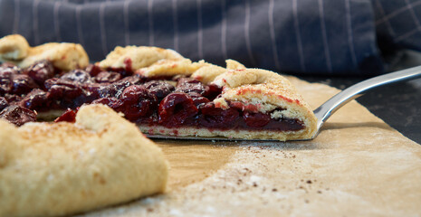 Summer homemade galette with cherries on parchment paper. Summer French open pie.                              