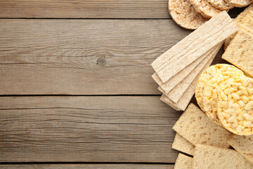 Various types of healthy whole grain crispbreads on grey wooden background.