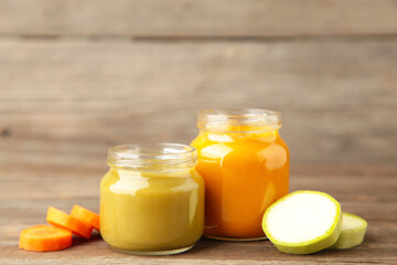 Glass jars with nutrient baby food on grey wooden background