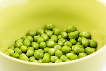 Green peas in a bowl, isolated on white background. Close-up