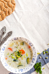 Creamy soup with vegetables in bowls on a white tablecloth top view. Vegetable vegetarian soup, rustic style. Free space for text. Tasty and healthy food.