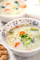 Creamy soup with vegetables in white bowls close-up. Vegetable vegetarian soup, rustic style. Tasty and healthy food.