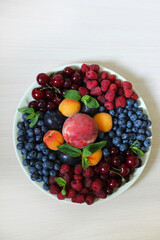 Mix of berries on the table on a white plate .Texture or background