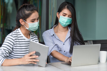 Two Asian young woman wearing medical mask to protect coronavirus while working at the outside