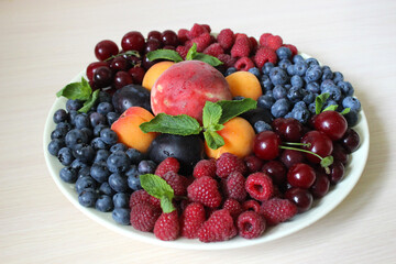 Summer mix of different berries on a light background on a white plate .Texture or background