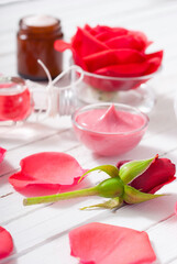 perfume, body care and beauty products with red roses, pink petals on white wood table
