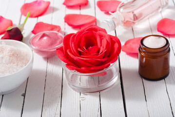 perfume, body care and beauty products with red roses, pink petals on white wood table