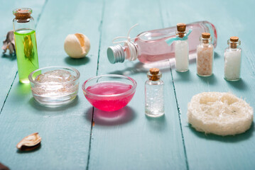 shampoo, shower gel, perfume and bath salt samples on wet old blue wood table background