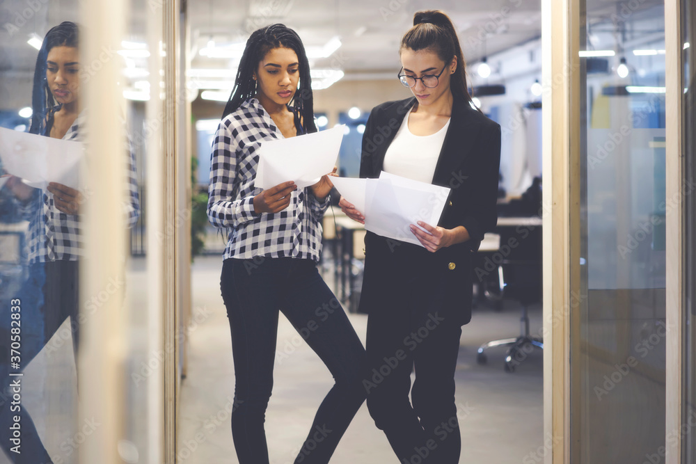 Poster pensive female business colleagues reading financial documentation discussing solutions together.pro
