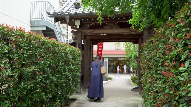 A Japanese woman walks along the path out of a Busdist temple in the traditional Kawagoe neighborhood of Tokyo, Japan. This neighborhood is one of the oldest in Tokyo, also called Little Kyoto.