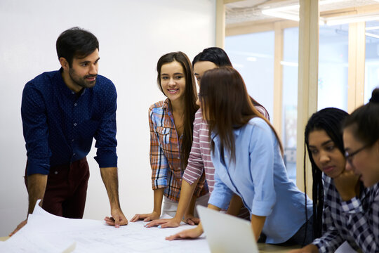International group of skilled students having brainstorming session about upcoming university seminar, male and female graphic designers planning working process and making blueprints for building