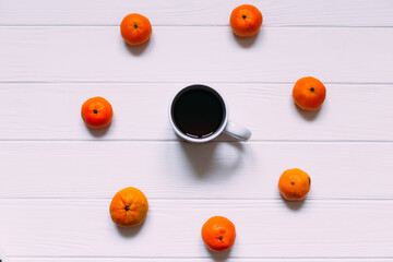 cup with hot drink and circle of tangerine on white surface. top