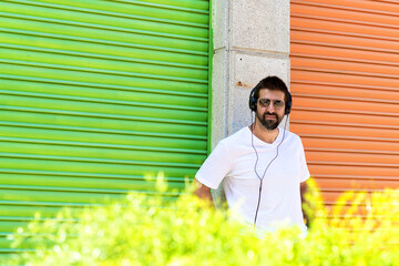 Cool trendy funny beard man in headphones listening music on colored background.