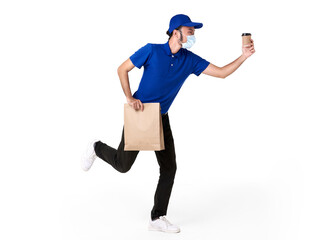 Asian delivery man wearing face mask in blue uniform running with paper bag and takeaway coffee isolated over white background. express delivery service during covid19.
