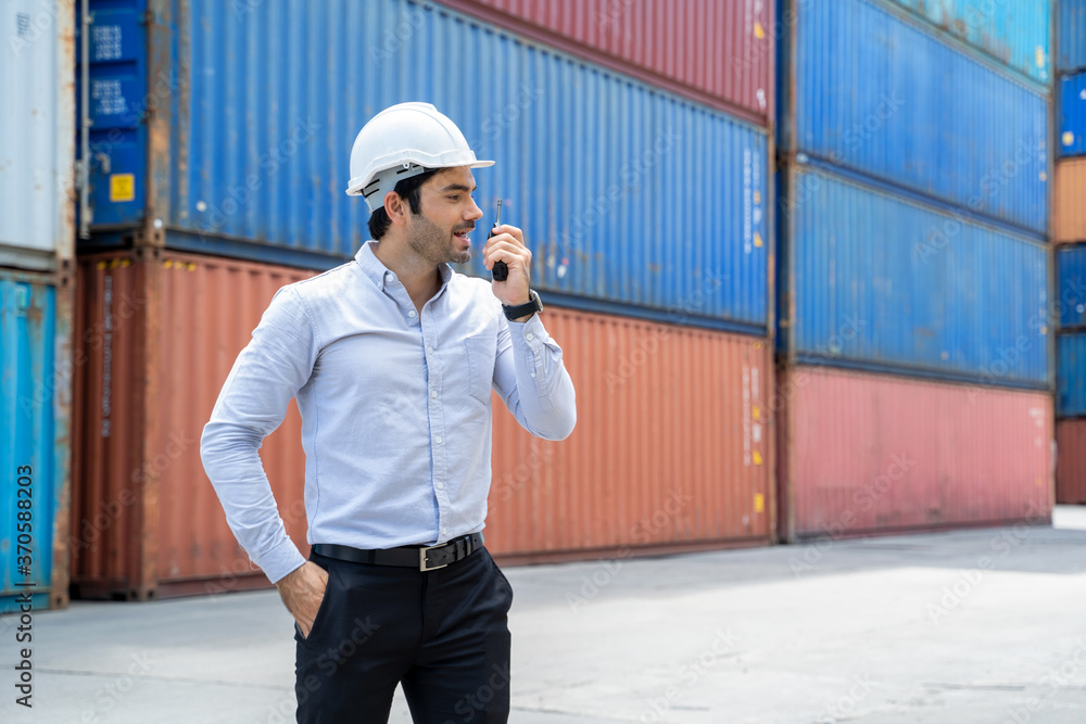 Poster businessman standing and using walkie talkie checking stock into container for loading in shipping p