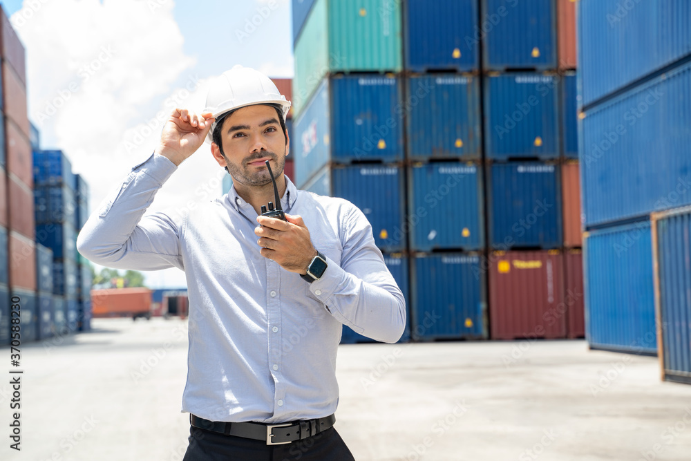 Poster businessman standing and using walkie talkie checking stock into container for loading in shipping p