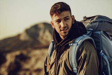 Obraz premium Young caucasian man traveler with big backpack hiking in the mountains